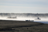 A tug boat tows a barge carrying trucks through morning mist on the River Ob near Aksarka. Yamal, Western Siberia, Russia