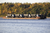 A barge carrying trucks being towed on the River Ob near Aksarka. Yamal, Western Siberia, Russia