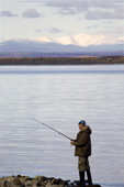An angler fishing in the River Ob at Gornoknyazevsk with the Ural mountains in the background. Yamal, Western Siberia, Russia