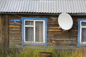 Old wooden house in Gornoknyazevsk with a satellite TV dish outside. Yamal, Western Siberia, Russia