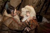 Emma Vanuito, a Nenets woman, dresses her daughter, Nenya, in traditional warm fur clothing so she can go outside and play in the cold. Tambey. Yamal Peninsula, Western Siberia, Russia.