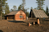 Log cabin at a Selkup summer camp in the forest with a traditional raised wooden food storage hut (right). Krasnoselkup, Yamal, Western Siberia, Russia