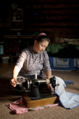 Lena Kuboleva, a young Selkup woman,using a sewing machine on the floor of her family's log cabin. Krasnoselkup, Yamal, Western Siberia, Russia