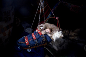 Two month old Nenets boy, Denis Serotetto, lies warmly wrapped in a traditional cradle, suspended from a tent pole inside the family's reindeer skin tent. Yamal, NW Siberia, Russia