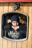 An Inuit boy looks out of the window of a fishing boat at Ilulissat. West Greenland