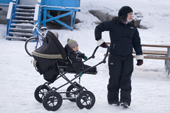 An Inuit mother with her baby in a pram in the centre of Ilulissat. West Greenland