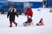 Two Inuit women pulling children on sleds through the centre of Ilulissat. West Greenland